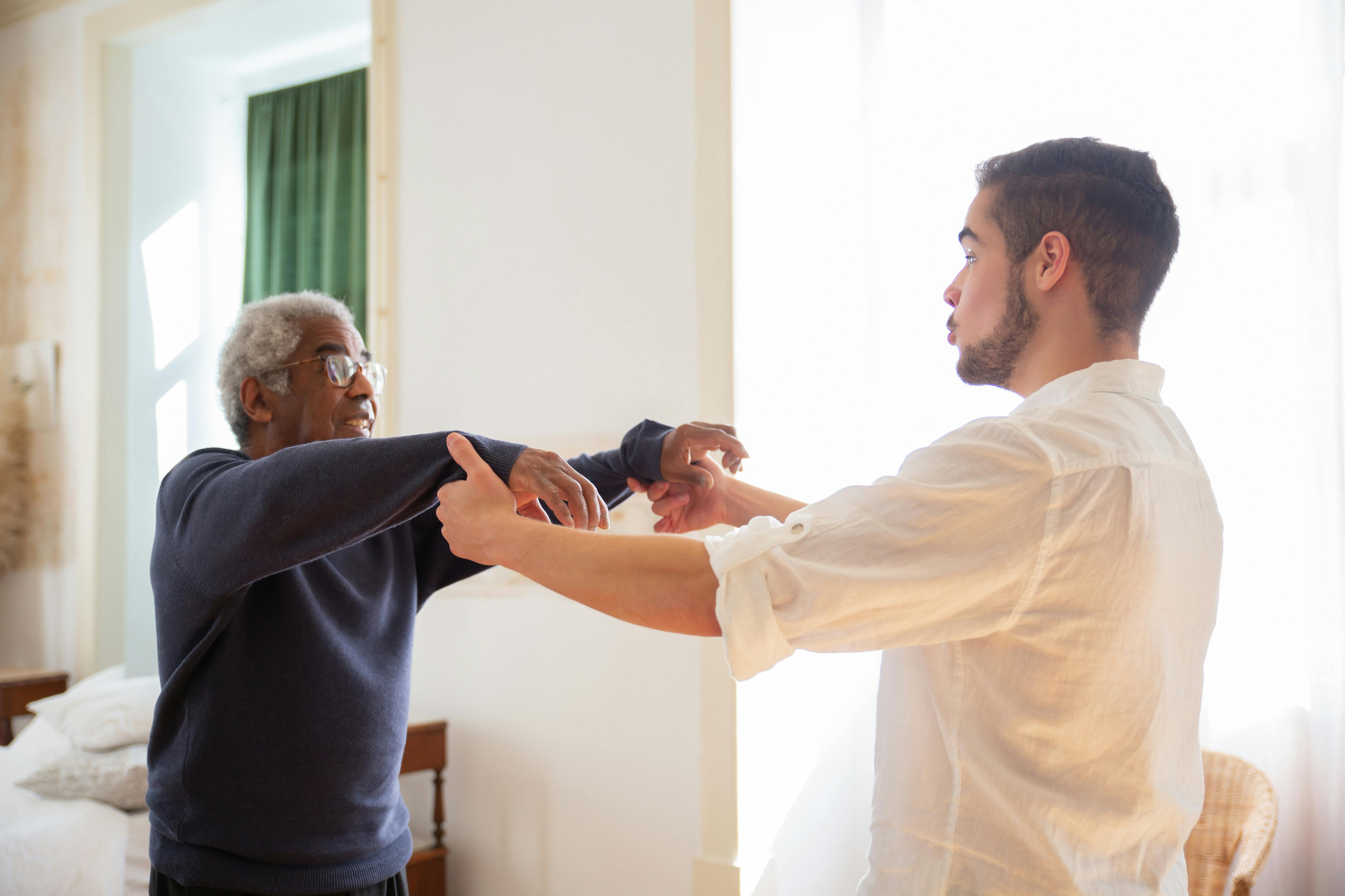 man assisted by caregiver in excercise
